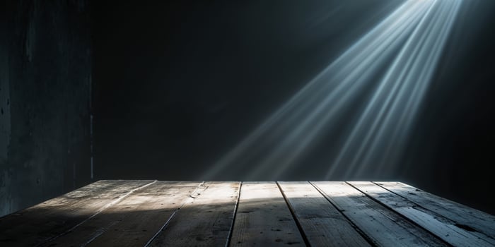 Light beams shine on a wooden tabletop in a dark space photo