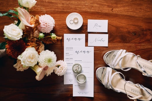 Amsterdam, Netherlands - June 5, 2024. Bride shoes stand on a wooden table next to the invitations and a bouquet of flowers. Top view photo