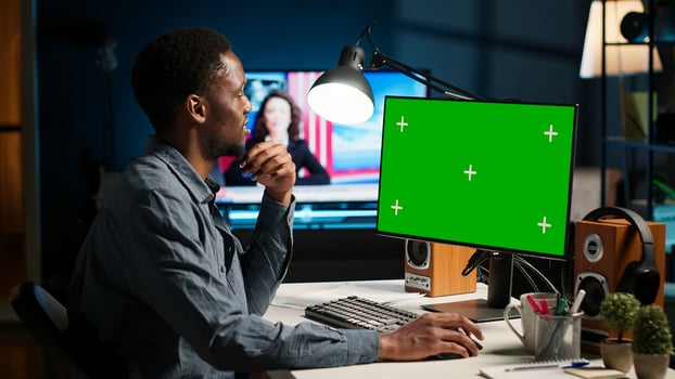 African american person working from home, checking green screen on PC, enjoys remote job at home office setup. Teleworker multitasking and networking in modern loft. Camera B. photo