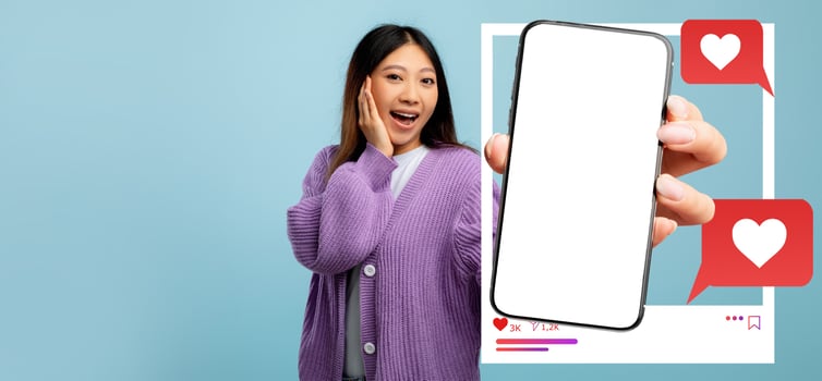 A young influencer holds a smartphone displaying a blank screen with heart icons and likes. She is excitedly engaging with her online audience, promoting social media interaction. photo