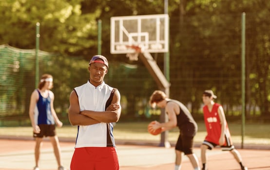 Serious African American basketball player and his multiracial team at outdoor court, empty space photo