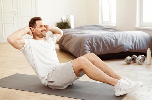 Stay Fit Concept. Man Exercising Doing Abs Sit-Ups Sitting On Gymnastics Mat Training At Home. photo