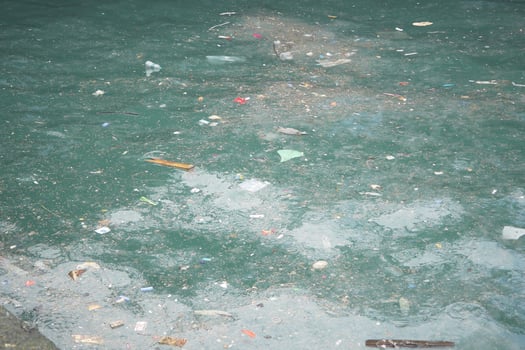 Water surface cluttered with debris in a polluted urban area photo