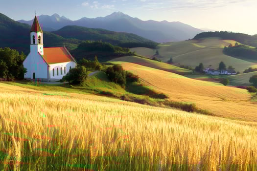 Golden wheat field surrounding idyllic church with mountains in background photo