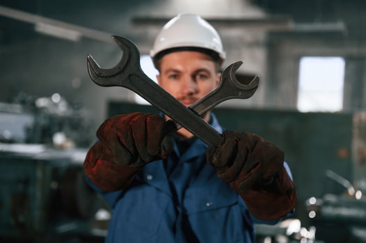 Holding two wrenches. Factory worker in ,blue uniform is indoors photo