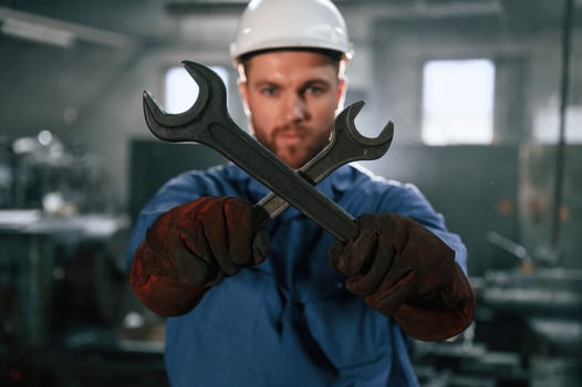 Holding ,two wrenches.. Factory worker in blue uniform is indoors photo