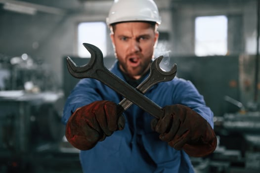 Holding, two wrenches. Factory worker in, blue uniform is indoors photo