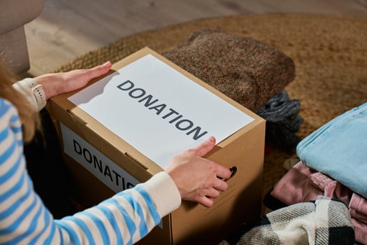 Woman packs cardboard donation box with clothes photo