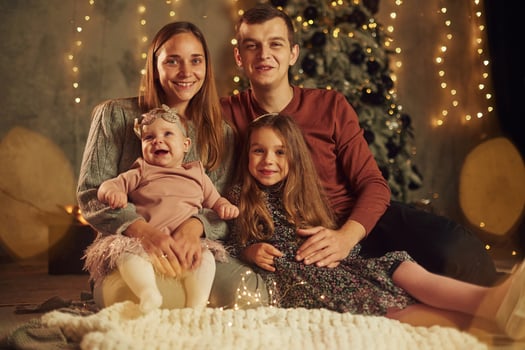Happy, family is sitting indoors, celebrating new year. With two little kids photo