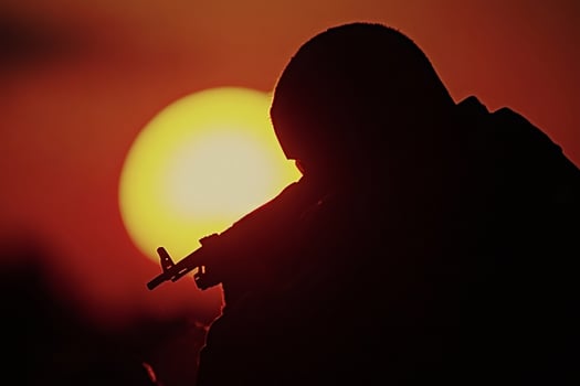 Soldier holding rifle during sunset, military conflict concept photo
