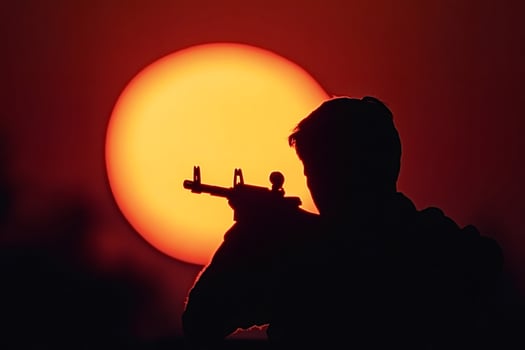 Soldier aiming with assault rifle at sunset silhouette photo