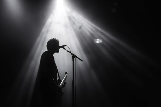 Musician singing and playing bass guitar under stage lights photo