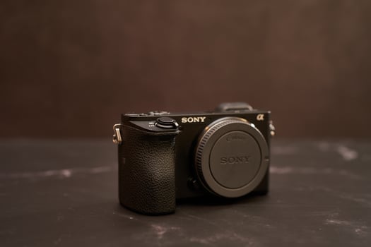 USA, Arizona - March 10, 2025. Sony A6300 digital mirrorless camera with a lens cap stands on a black marble table photo