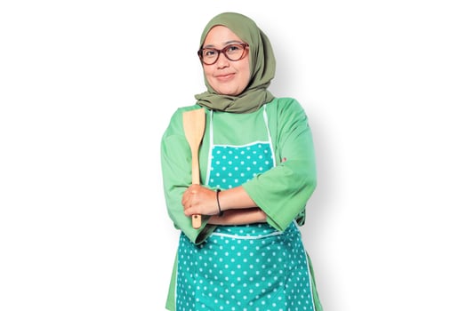 Confident Muslim woman chef wearing apron holding a wooden spoon smiling photo