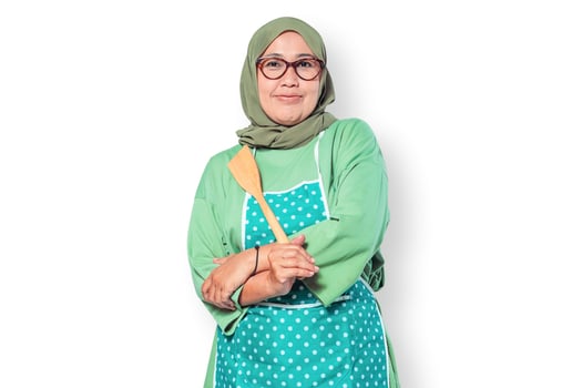 Smiling Muslim woman chef wearing an apron holding a wooden spatula confidently photo