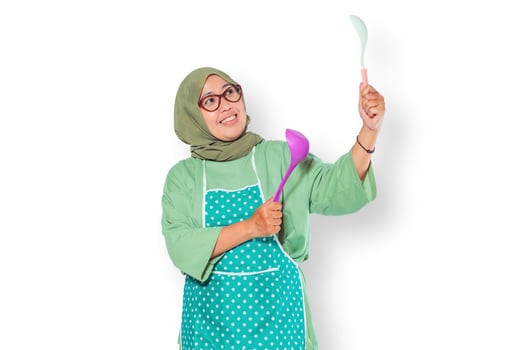 Smiling Muslim Woman Cooking with Kitchen Utensils photo
