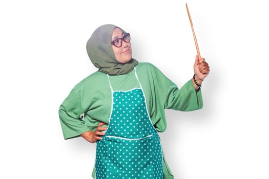 Happy Muslim woman wearing a hijab and apron, holding a wooden spoon in a cooking pose photo