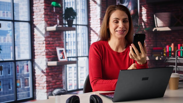 Cheerful woman attends online class via conference on smartphone, meeting with teacher for important virtual lesson. Person studying for master degree on mobile device. Camera B. photo