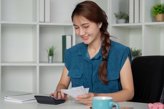 Financial Planning and Organization. A happy individual reviewing expenses with a smile while managing finances. photo