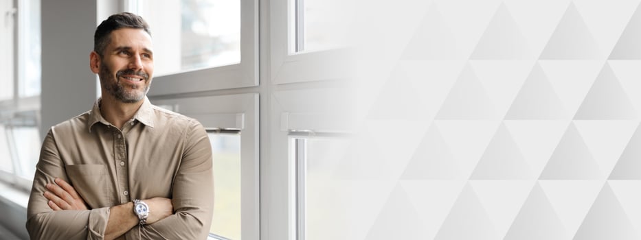 A middle aged businessman stands by a large window in a corporate office, smiling confidently as he reflects on his achievements while enjoying a moment of contemplation in his workspace, copy space photo