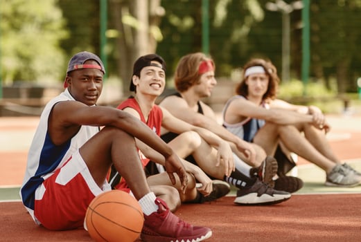 Multiracial team of basketball players getting some rest after their game at outdoor court, free space photo
