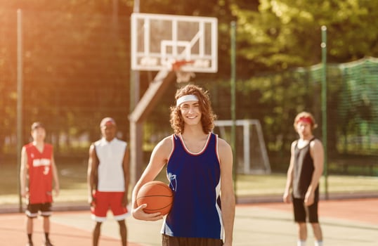 Handsome millennial player and his multinational team ready to play ball at outdoor basketball court photo