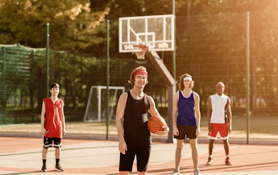 Happy Caucasian sportsman holding ball with his diverse team at basketball arena outdoors photo
