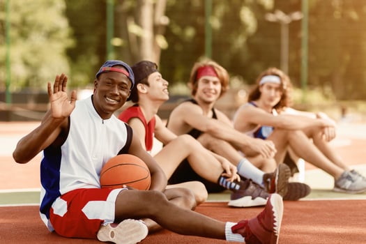 Happy African American basketballer and his multiracial team relaxing after match at outdoor stadium, blank space photo