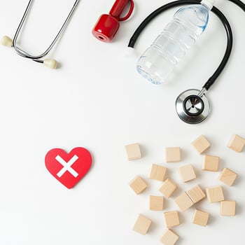 Healthcare Wellness Flat Lay with Stethoscope, Water Bottle, Dumbbell, Heart with X Symbol and Wooden Blocks photo