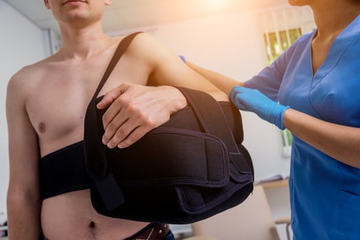 Nurse putting a sling on patients arm that is broken. Injury photo