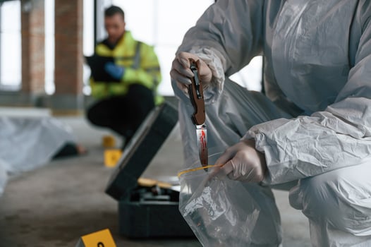 Putting,, the knife into bag. Detectives are collecting evidence in a crime scene near dead body photo