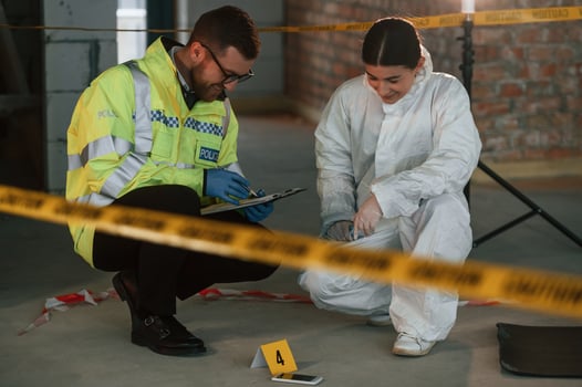Sitting and laughing. Two detectives are collecting evidence in a crime scene. Forensic specialists are making expertise photo