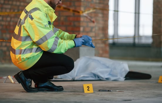 Wearing, gloves.. Male detective is collecting evidence in a crime scene near dead body on the construction site photo