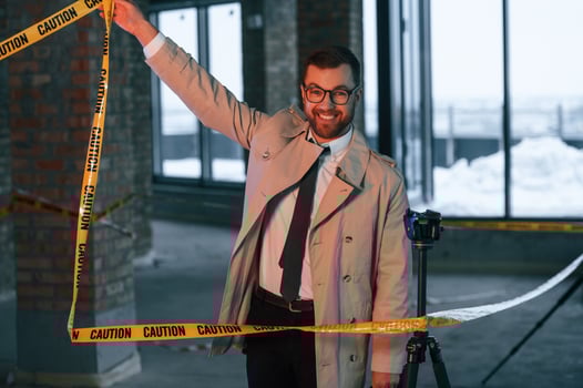 Positive detective in coat is holding caution police tape and smiling photo