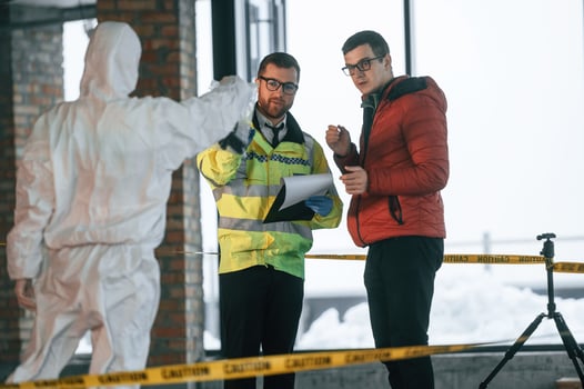 The witness is being questioned. Two detectives are collecting evidence in a crime scene photo