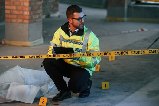 Male detective is collecting, evidence, in a crime scene near dead body on the construction site. Sitting with notepad in hands photo