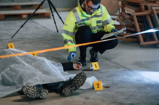 Knife ,is on the floor.. Male detective is collecting evidence in a crime scene near dead body on the construction site photo