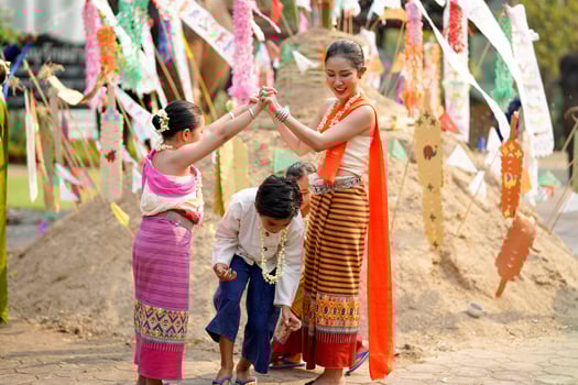 Group of Thai children's with beautiful Thai young woman and in the Thai traditional dress playing human cave train on outdoor at the Songkran festival. photo