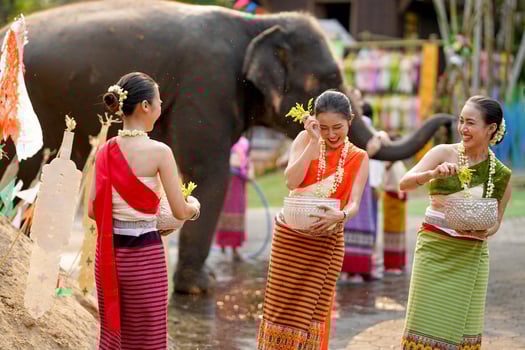 Group of beautiful Thai women in the Thai traditional dress playing to sprinkle water on the Thai New Year's Day or Songkran festival with elephant outdoor photo