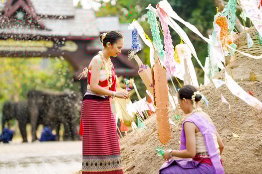 Beautiful Thai women in the Thai traditional dress help stick the triangular flag on the sand pile in temple in Songkran festival. photo