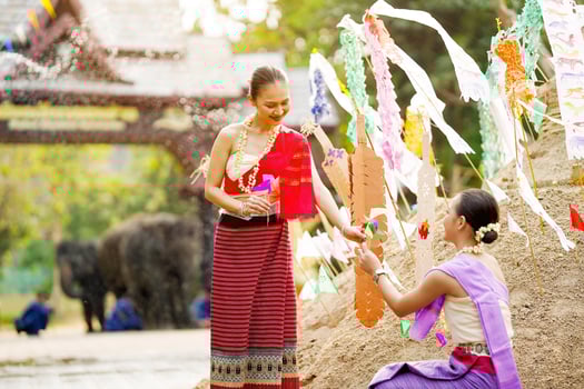 Beautiful Thai women in the Thai traditional dress help stick the triangular flag on the sand pile in Songkran festival. photo
