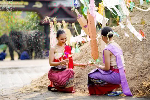 Beautiful Thai women with the Thai traditional dress help stick the triangular flag on the sand pile in temple in Songkran festival. photo