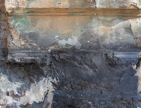 An old wall features weathered paint and plaster, revealing a rich and textured surface. photo