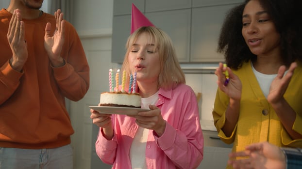 Smiling multiracial friends multiethnic people congratulate diversity man women African American guy Caucasian girls females males at home celebrating birthday party woman blowing candles cake joy photo