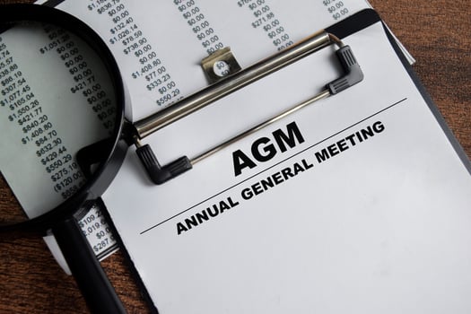 Concept of AGM - Annual General Meting write on paperwork isolated on Wooden Table. photo