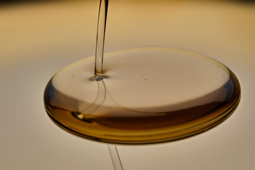 Texture of pouring cosmetic oil on a golden background. photo