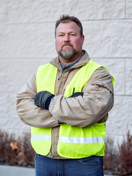 Confident Male Worker in Safety Vest Poses Outdoors with Crossed Arms photo