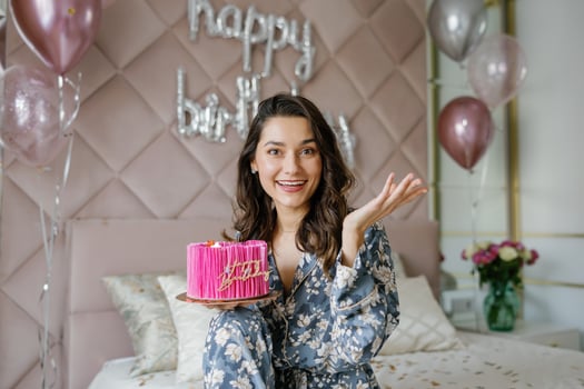Excited woman showing birthday cake celebrating at home photo