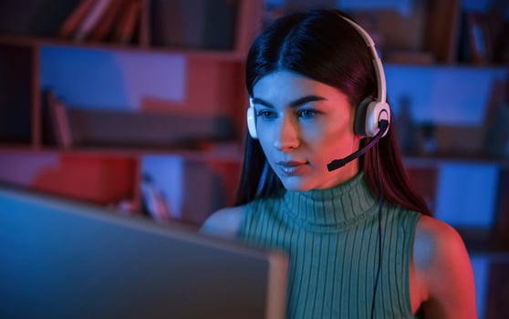 Young woman, in headphones is sitting by a pc. Neon lighting photo