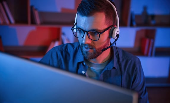 Read ,and blue neon lighting. Man is sitting by a computer indoors at home photo